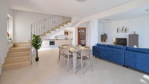 Um apartamento moderno com escada, área de refeições, sala de estar com sofá azul e cozinha.