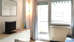 A room with a television on a wooden cabinet, a map on the wall, a sliding glass door to the outside, and a radiator below the door. - 2 bedroom lovely apartment in Lavagna (Lavagna)