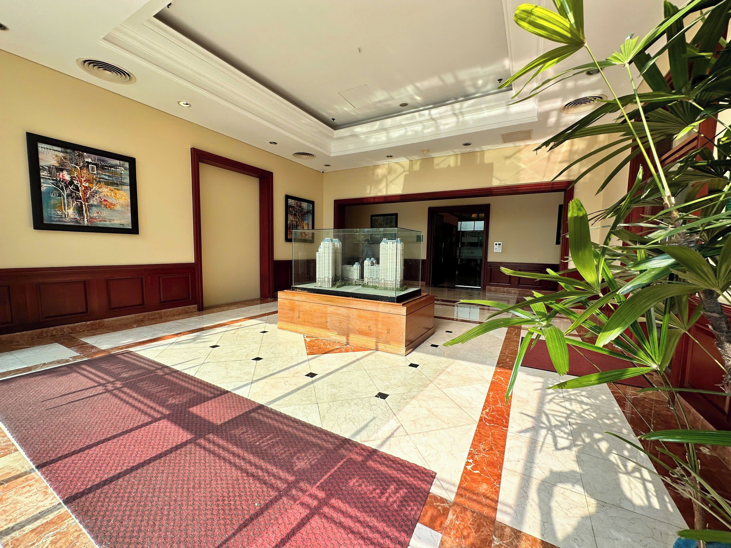 A lobby with a tiled floor, a glass display case, and a large plant.