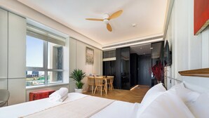 A modern hotel room with a large bed, a dining table, and a view of the city through the window. - free pool the manor luxury condotel (Ho Chi Minh City)