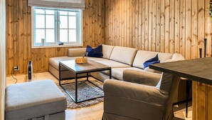 A cozy room with a wooden paneled wall, a sofa, a coffee table, and a window with a view.