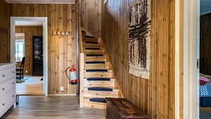 A wooden interior with a staircase, a fire extinguisher, and a storage box.