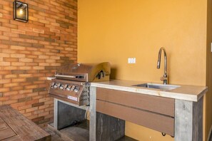 A brick wall with a built-in grill and a sink with a faucet.