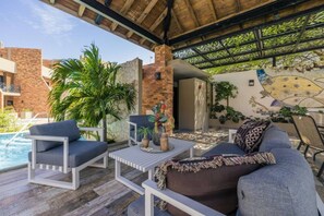 An outdoor seating area with a pool, lounge chairs, and a decorative wall.