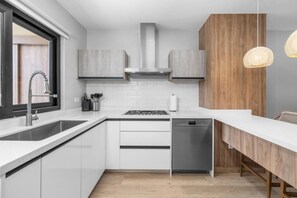 A modern kitchen with white cabinetry, a stainless steel sink, and a built-in dishwasher.