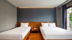 Habitació d'hotel amb dos llits individuals, un capçal de llit de fusta, una petita taula de nit i una finestra amb cortines.