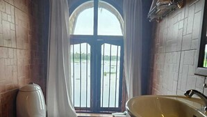 Ein Badezimmer mit Toilette, Waschbecken und einem Fenster mit Vorhängen.