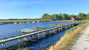A calm waterway with boats docked, a wooden pier, and red buildings in the background.