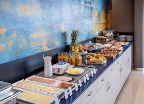 A buffet with various food items, including fruits, cheeses, and meats, arranged on a counter with a blue and white color scheme. - Hotel Sercotel Plana Onda (Onda)
