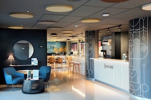 Un moderno vestíbulo de hotel con mostrador de recepción, zona de estar y bar.