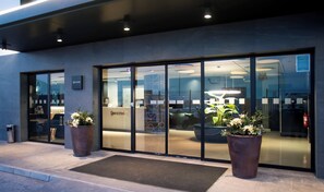 A modern hotel entrance with a reception desk, large glass doors, and potted plants. - Hotel Sercotel Plana Onda (Onda)