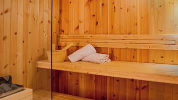 Una sauna de fusta amb bancs i una barra amb tovellons.