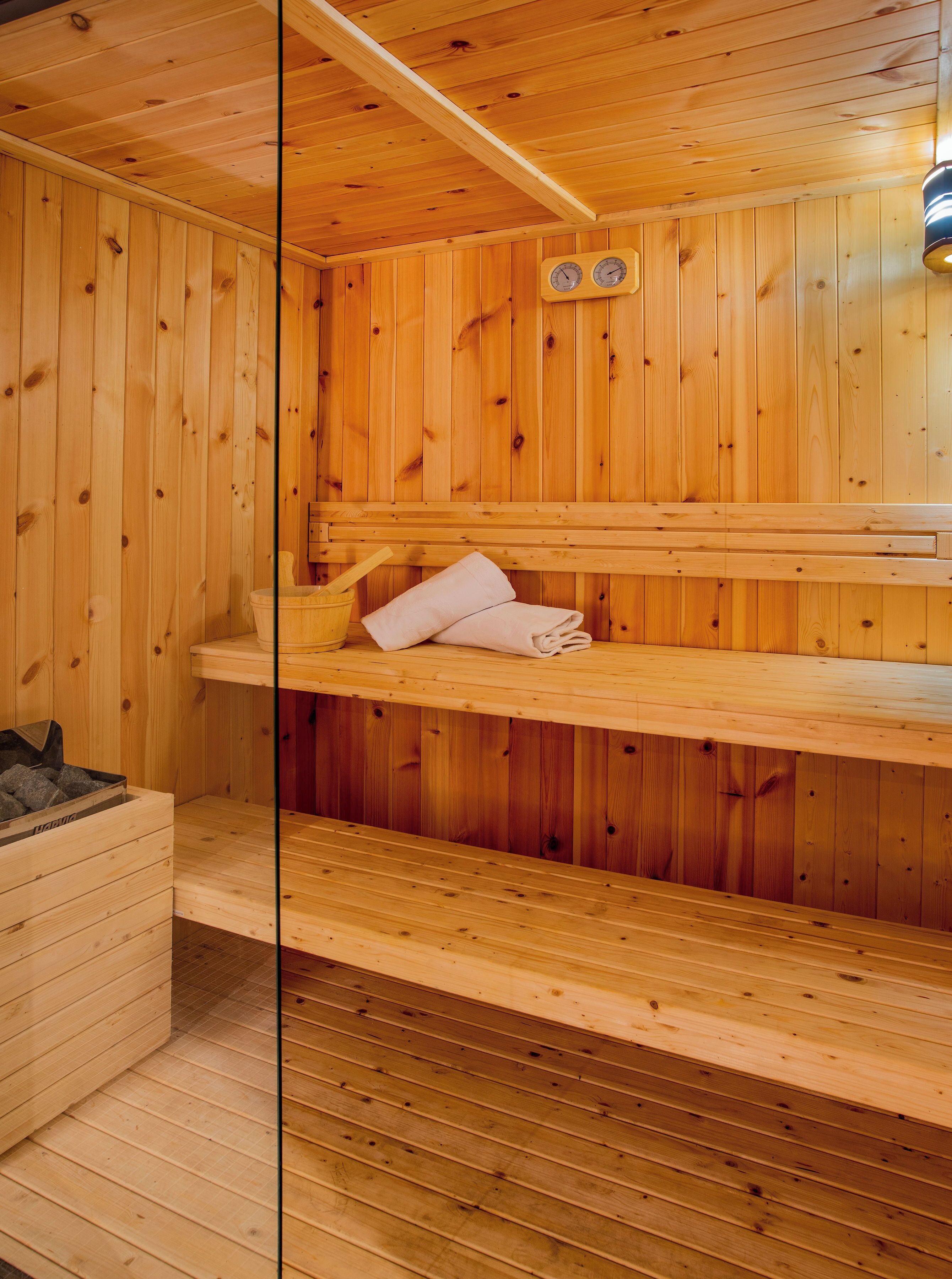 A wooden sauna with benches and a bench seat, a wooden wall, and a wooden floor.