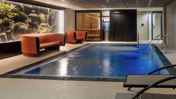 Una piscina interior con suelo de baldosas, una fuente de agua y zonas de descanso.