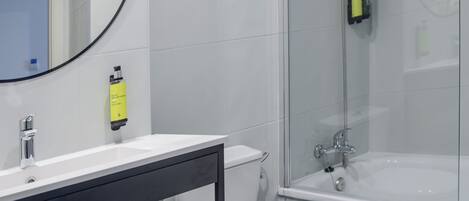 A modern bathroom with a white sink, toilet, and glass-enclosed shower.