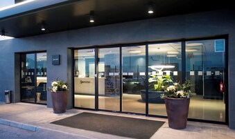 Una entrada de hotel moderna con puertas de vidrio, mostrador de recepción e instalaciones con plantas.