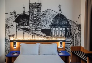 A hotel room with a bed, bedside tables, a wall-mounted lamp, and a decorative wall mural. - Hotel Sercotel Plana Onda (Onda)