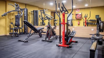 Un gimnasio con diversos equipos de ejercicio, incluyendo una máquina de remo, una prensa de piernas y una bicicleta estática.