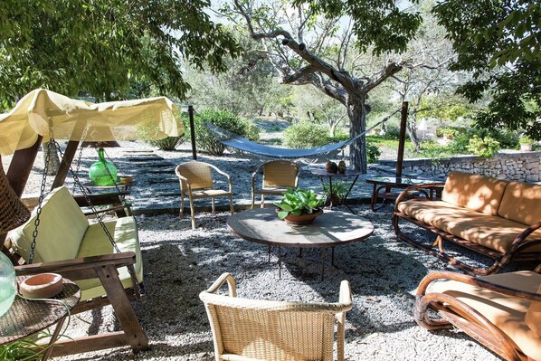 A patio with wicker furniture, a hammock, and a stone wall.