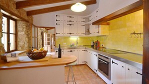 Cozinha com armários brancos, bancada de madeira, pia e fogão.