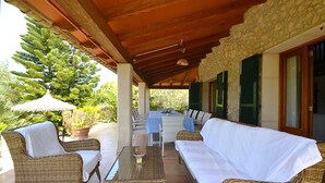 A covered outdoor seating area with wicker furniture, a table, and a potted plant. - Villa in Majorca near Tramuntana Mountains (Manacor de la Vall)