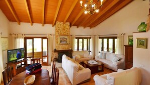 A spacious living room with a fireplace, wooden ceiling beams, and a television. - Villa in Majorca near Tramuntana Mountains (Manacor de la Vall)