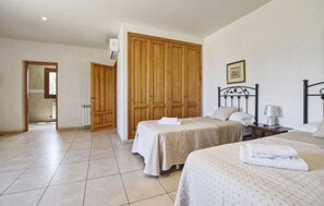 Une chambre avec deux lits, une armoire en bois, un radiateur et un tableau encadré au mur.
