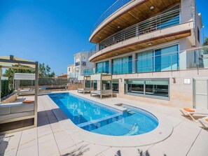 Ein modernes Gebäude mit Pool, Sitzgelegenheiten im Freien und einem überdachten Bereich.