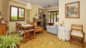 Ein geräumiges Wohnzimmer mit einem Holzesstisch, Stühlen, einem Kamin und einem Fernseher.