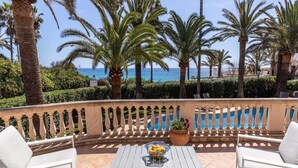 Una terraza con muebles blancos, una piscina y vistas al mar.