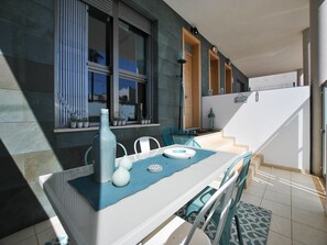A modern kitchen with a white countertop, blue tablecloth, and potted plants.