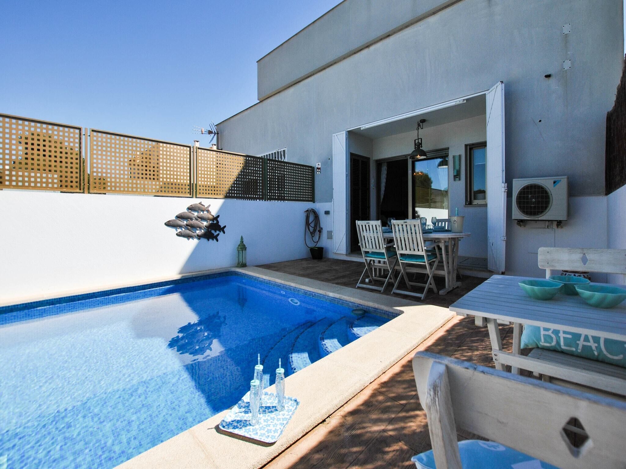 Un espace piscine extérieur moderne, doté d’une piscine à l’eau d’un bleu limpide, d’une terrasse en bois et d’une table avec des chaises.