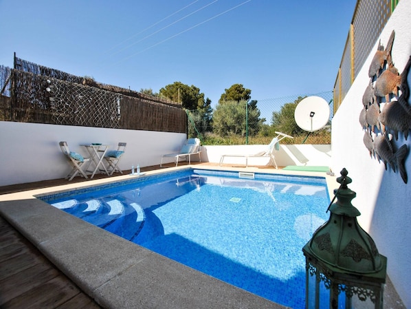 A swimming pool with lounge chairs and a decorative lantern.