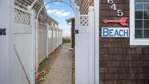 A narrow pathway leading to a gated entrance with a 'Beach' sign and a directional arrow pointing left. - Ultimate Oceanfront Escape for Two at Beachy Eagle B, Amazing Views, Fire-Table, Steps from Beach (Rockaway Beach)