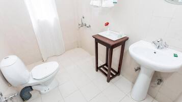 Un baño pequeño con inodoro, lavamanos y ducha.