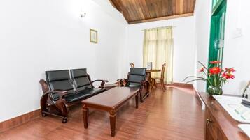 Una habitación con techo de madera, un conjunto de sofás, una mesa de comedor y una pequeña cocina.