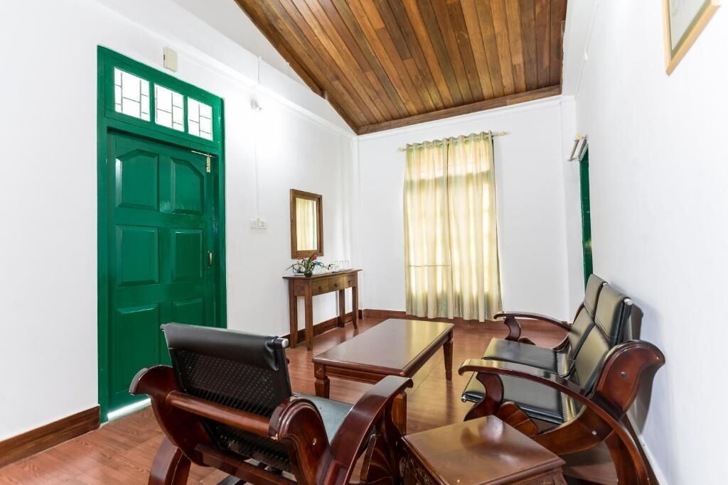 A room with a green door, wooden ceiling, a wooden table, and two leather chairs.