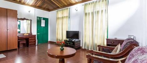 A spacious living room with a wooden ceiling, a green door, a television, and a sofa.
