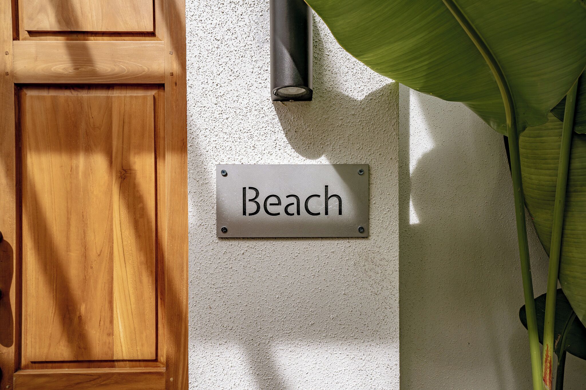 A wooden door and a sign that reads "Beach" on a textured wall.