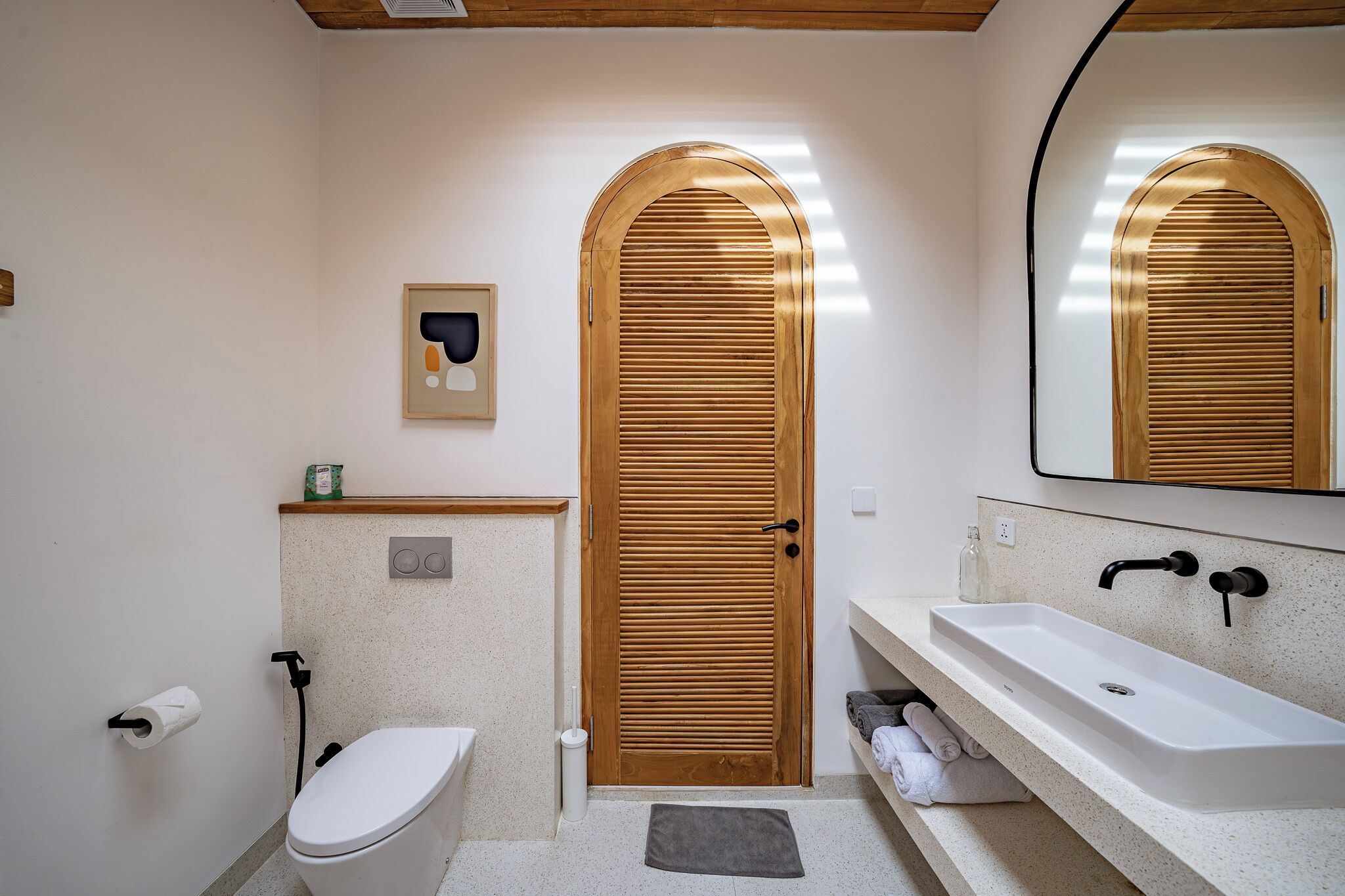 A bathroom with a wooden door, a white sink, and a mirror.