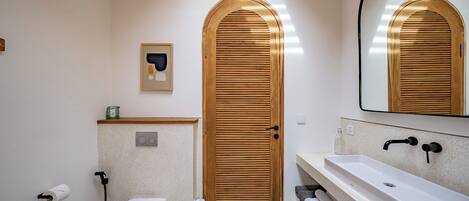 A bathroom with a wooden door, a white sink, and a mirror.