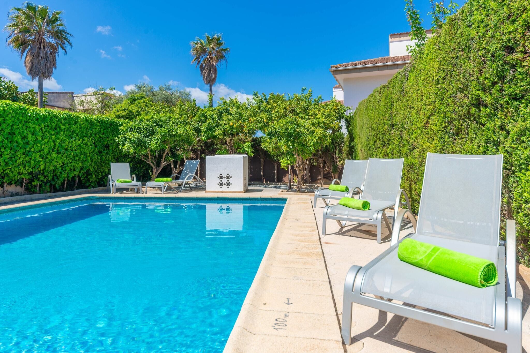 Une piscine avec des chaises longues et une haie.