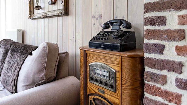 Ein altes Radio auf einer Holzschublade in einem Raum mit Backsteinwand und Holzvertäfelung.