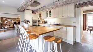 Une cuisine moderne avec des meubles blancs, un îlot central en bois doté de tabourets et des murs en briques apparentes.