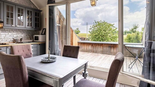 Une cuisine moderne avec des meubles gris, un pare-feu en pierre et un coin repas comprenant une table et des chaises.