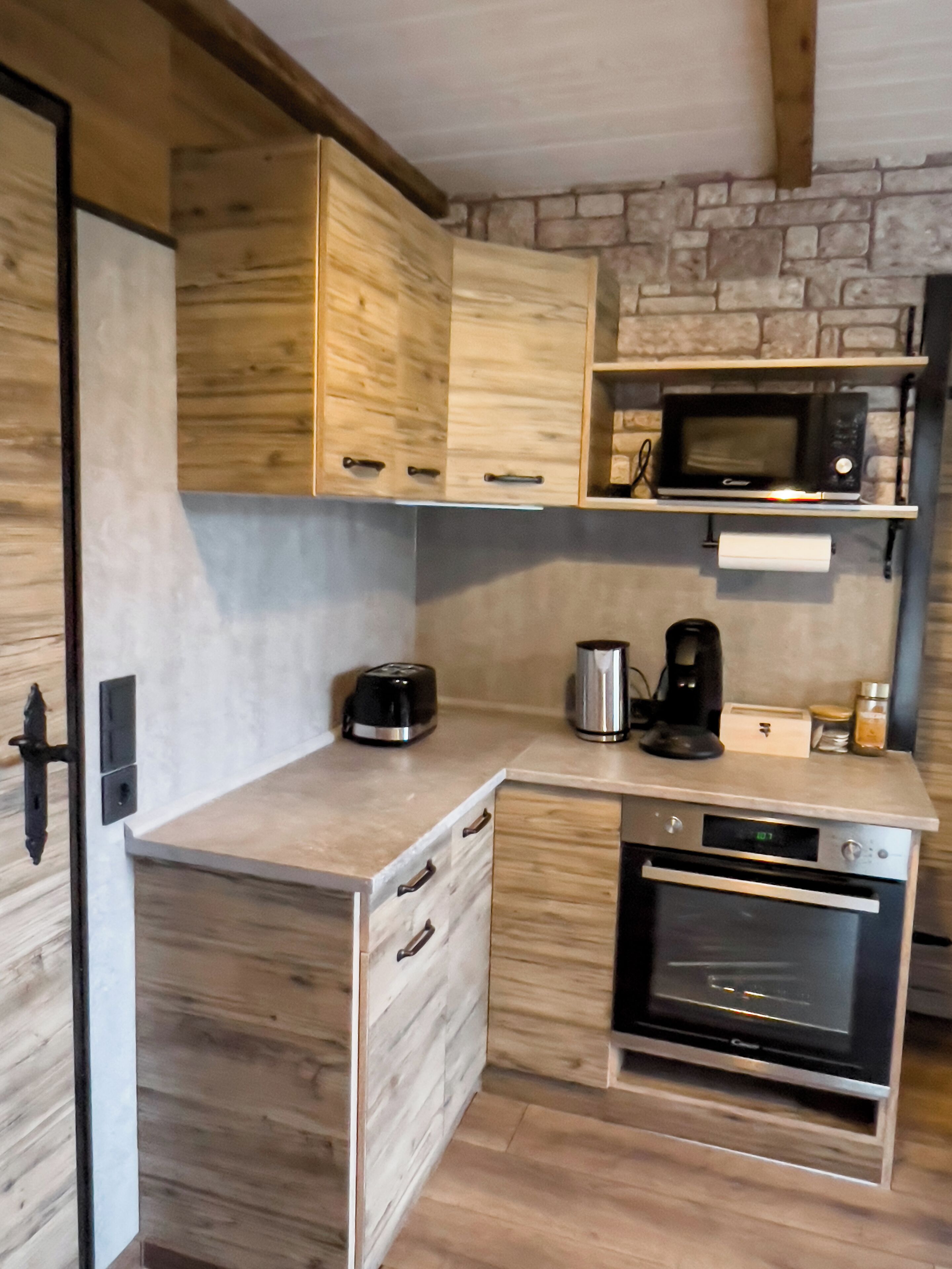 A compact kitchen with wooden cabinets, a microwave, a coffee maker, and an oven.