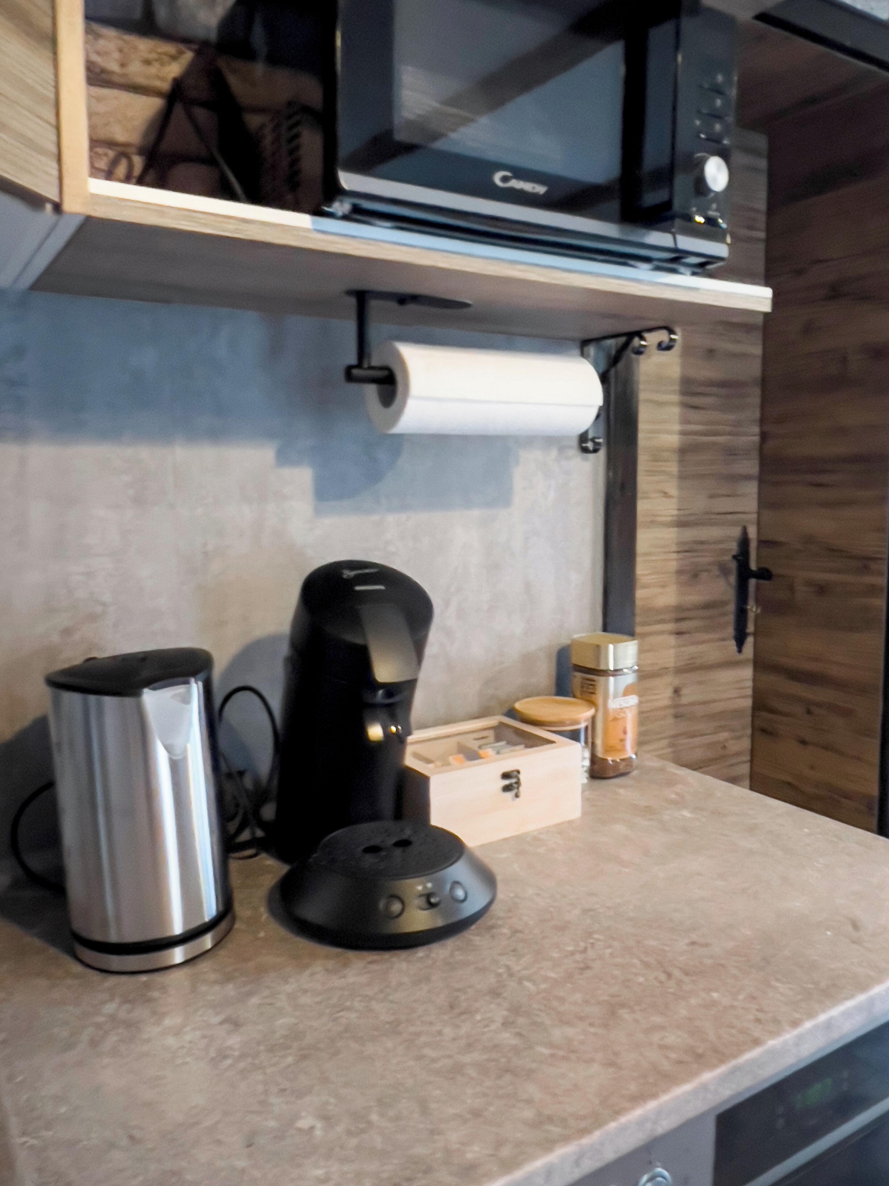 A kitchen counter with a coffee maker, a kettle, and a jar of spices.