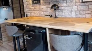Una cucina con parete in pietra, televisore a schermo piatto, piano di lavoro in legno, sgabelli da bar e lavastoviglie.