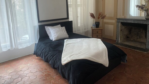 A bedroom with a bed, a nightstand, a fireplace, and a window with curtains. - Bed and breakfast in a small chateau in the Loire Valley (Saint-Cyr-en-Pail)