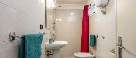 Un baño con ducha, lavabo, inodoro y espejo.
